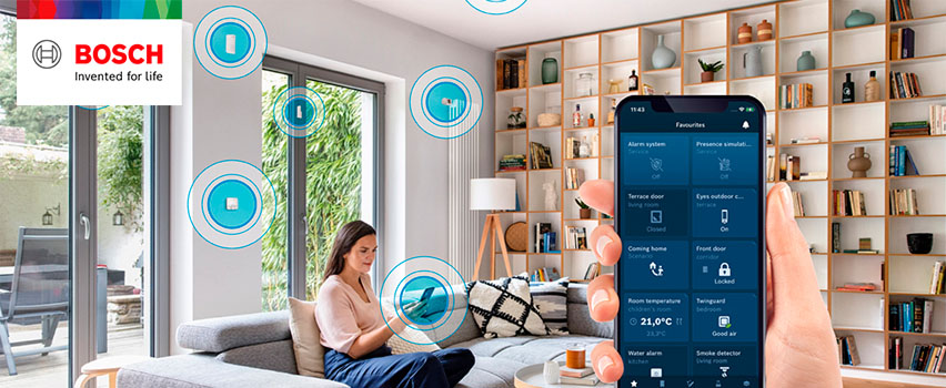 Bosch Smart Home -sovellus näyttää suosikit kuten hälytys, ovet, huonelämpötila ja palovaroitin älykodissa naisen kanssa sohvalla