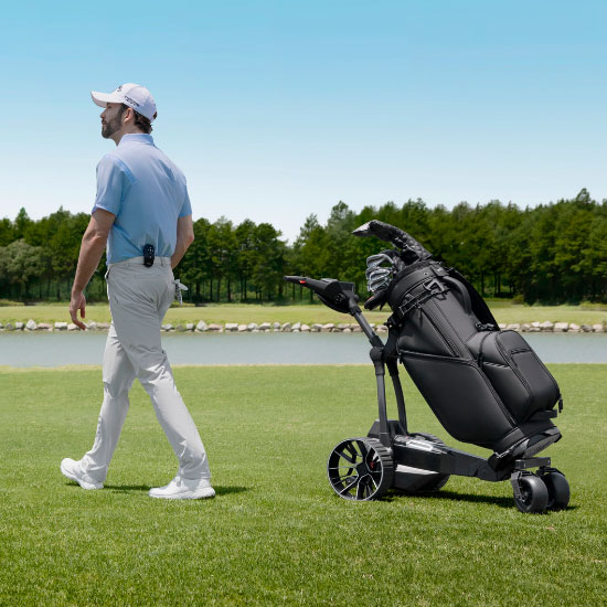Golfaaja kävelee golfkentällä Navee-sähkögolfkärryn vieressä, jossa on golfbagi