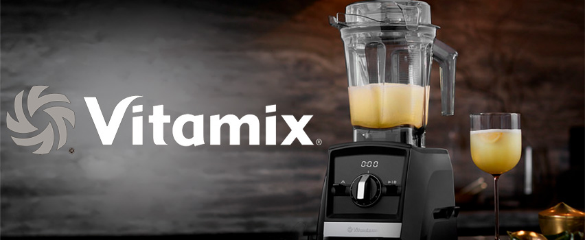 Vitamix tehosekoitin keltaisella smoothiella astiassa ja lasissa logon vieressä sloganilla Uudet seikkailut odottavat
