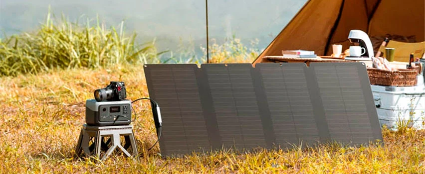 EcoFlow RIVER 2 virta-asema ja aurinkopaneeli teltan vieressä niityllä – kompakti off-grid-energiaratkaisu retkeilyyn
